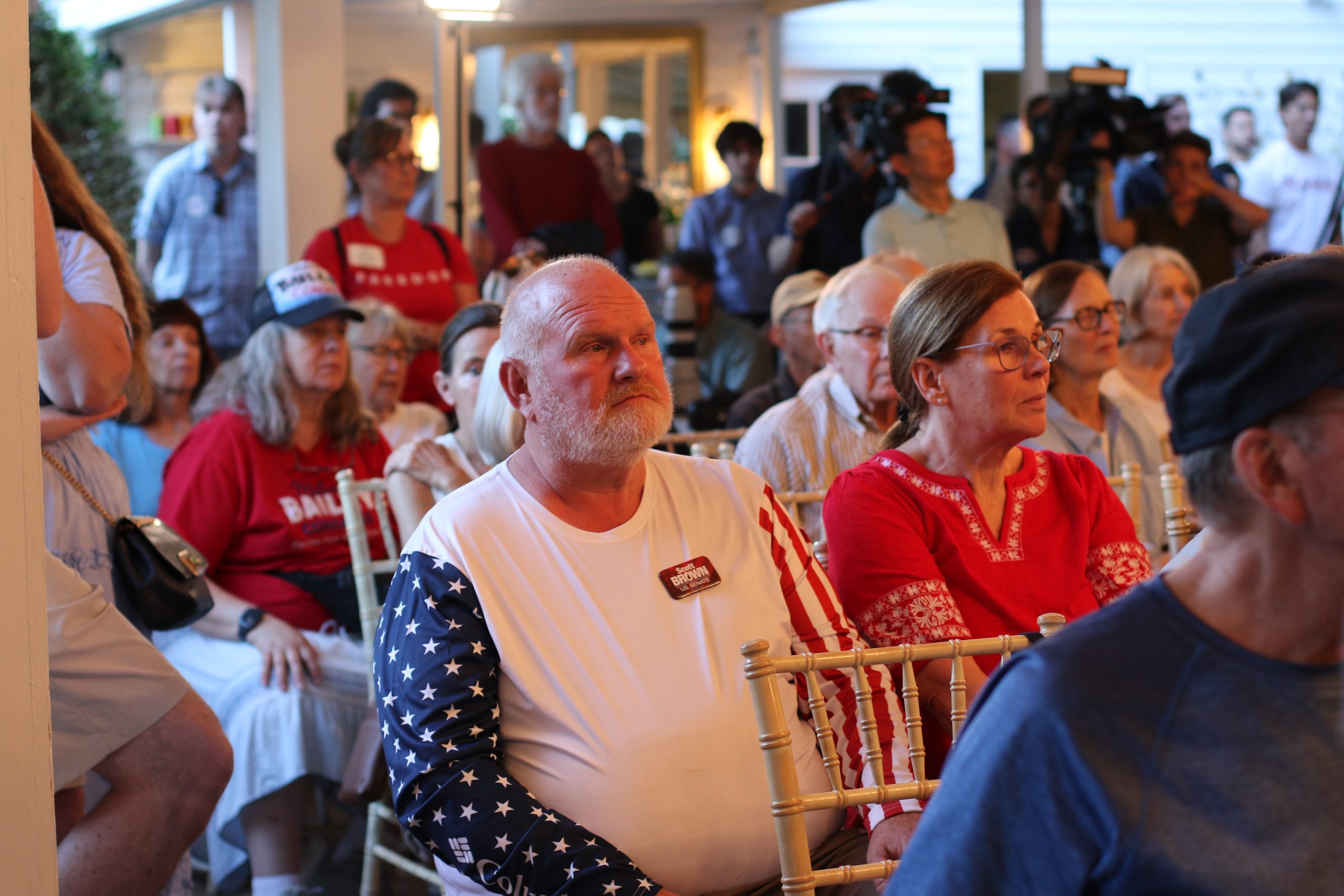 Mark Nowack and his wife, Cynthia Palaro, watch a debate between John E. Sununu and Scott Brown on Wednesday, June 24, 2026. The couple likes both candidates but say Brown has their vote.