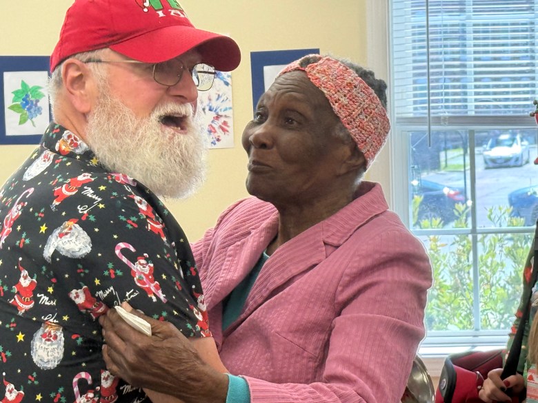 Christine Jean beams as she greets Santa Claus, played by John Stone, with a hug.