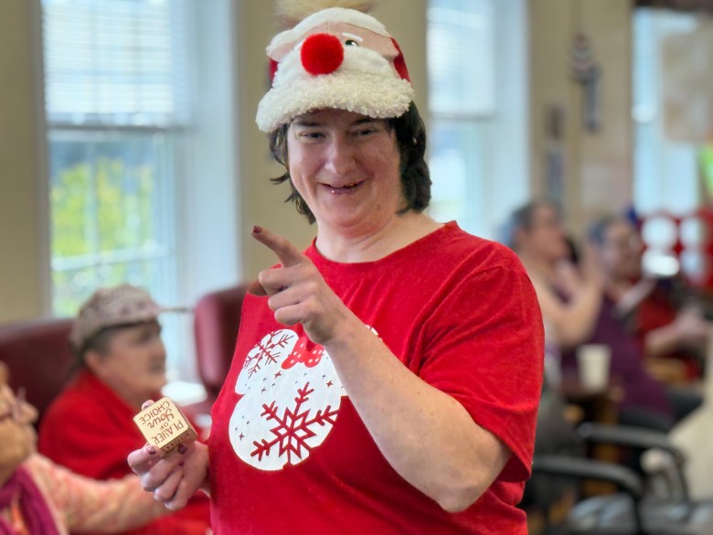 Laurie Vaillancourt gets up to dance with Santa, donning a Christmas-themed hat.