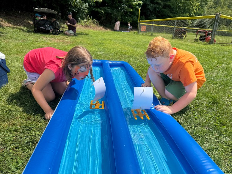 Madelynn Martel and Daxton Martel of Rindge blow on their paper sailboats in a race against each other.