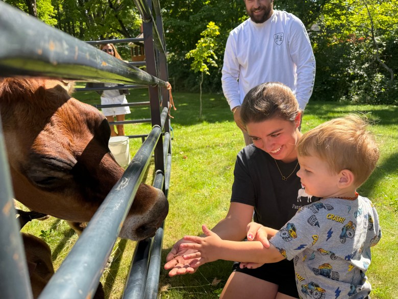 Rebecca Traffie, owner of Patricia's Ark, helps Lukas Mahoney of Peterborough feed one of her cows.