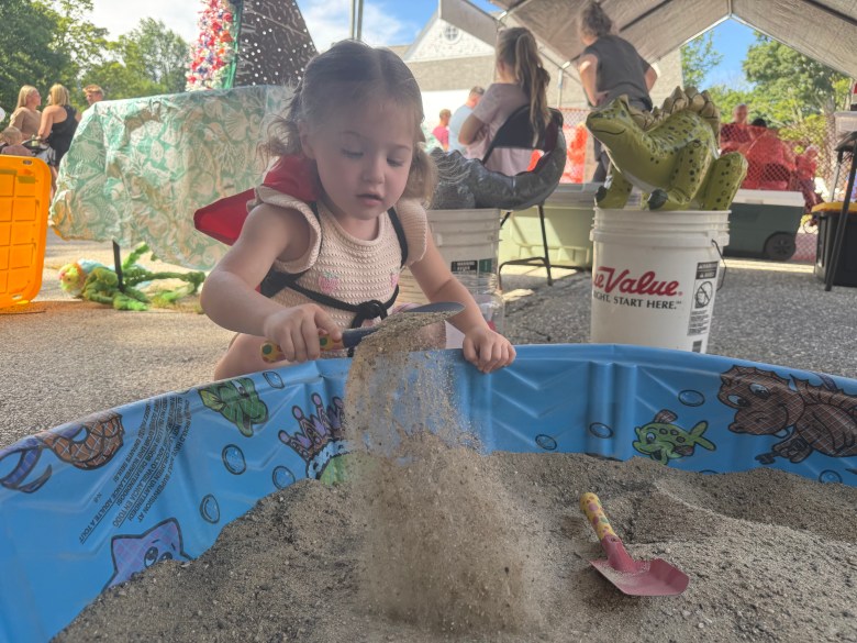 Macy Teixeira of New Ipswich digs for dinosaur eggs at the Dino Dig game.