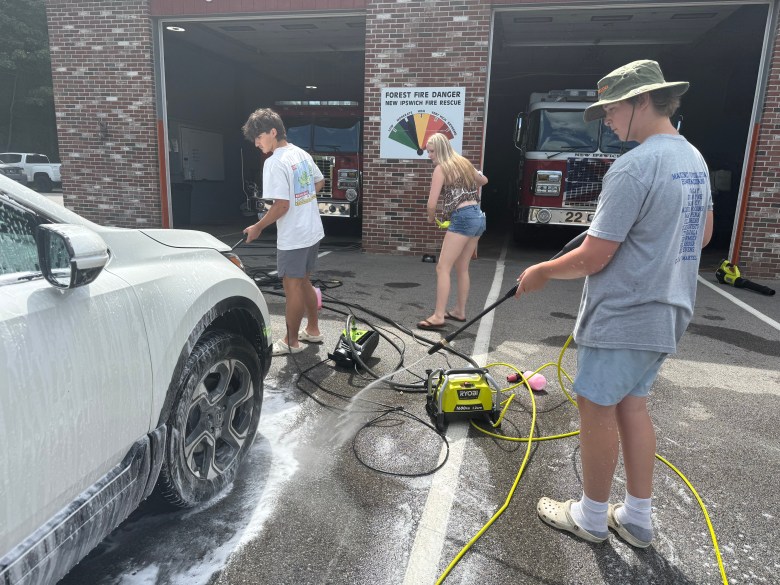Cayden Emerson, Molly Lyons and Reed Carignan wash a car together.