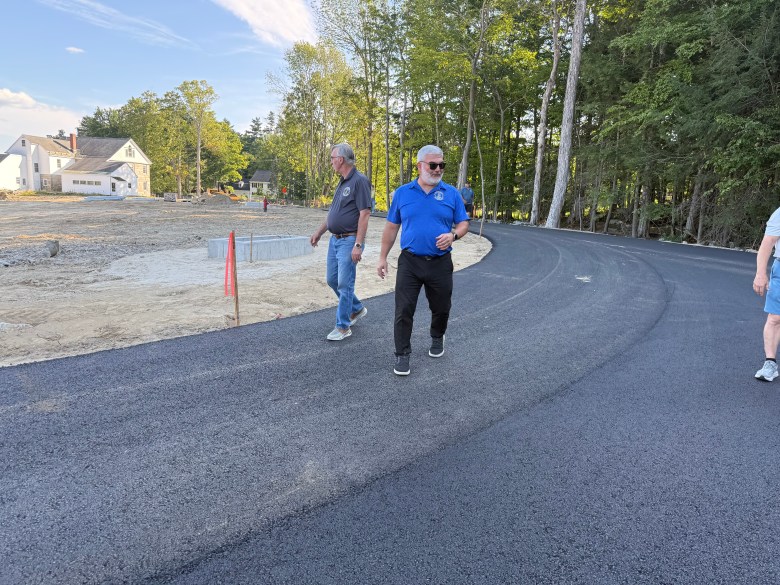 Members of the Select Board and the public walk a road on a proposed development on Main Street.