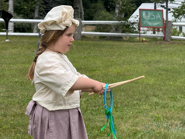 Clara Whitcomb plays a stick and hoop toss game.