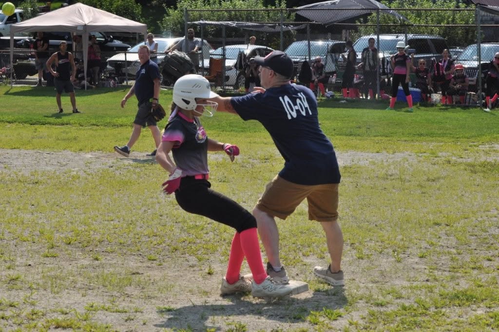 Madison Shuttle reaches the base safely as firefighter Scott Jenkins calls for the ball.