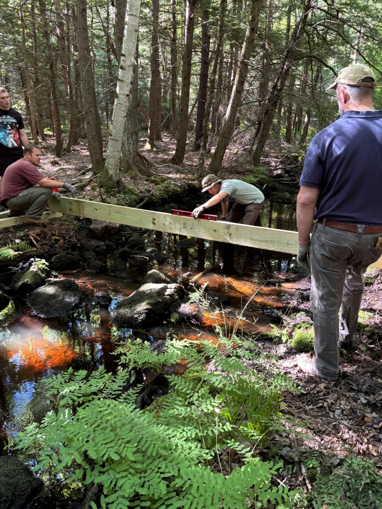 Scout John Sementa making sure the bridge the bridge is level, with help from scoutmaster Jason Paolino.