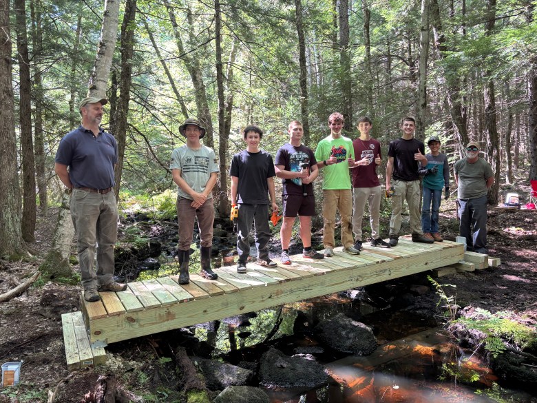 Younger scouts and other youth standing on the completed foot bridge.