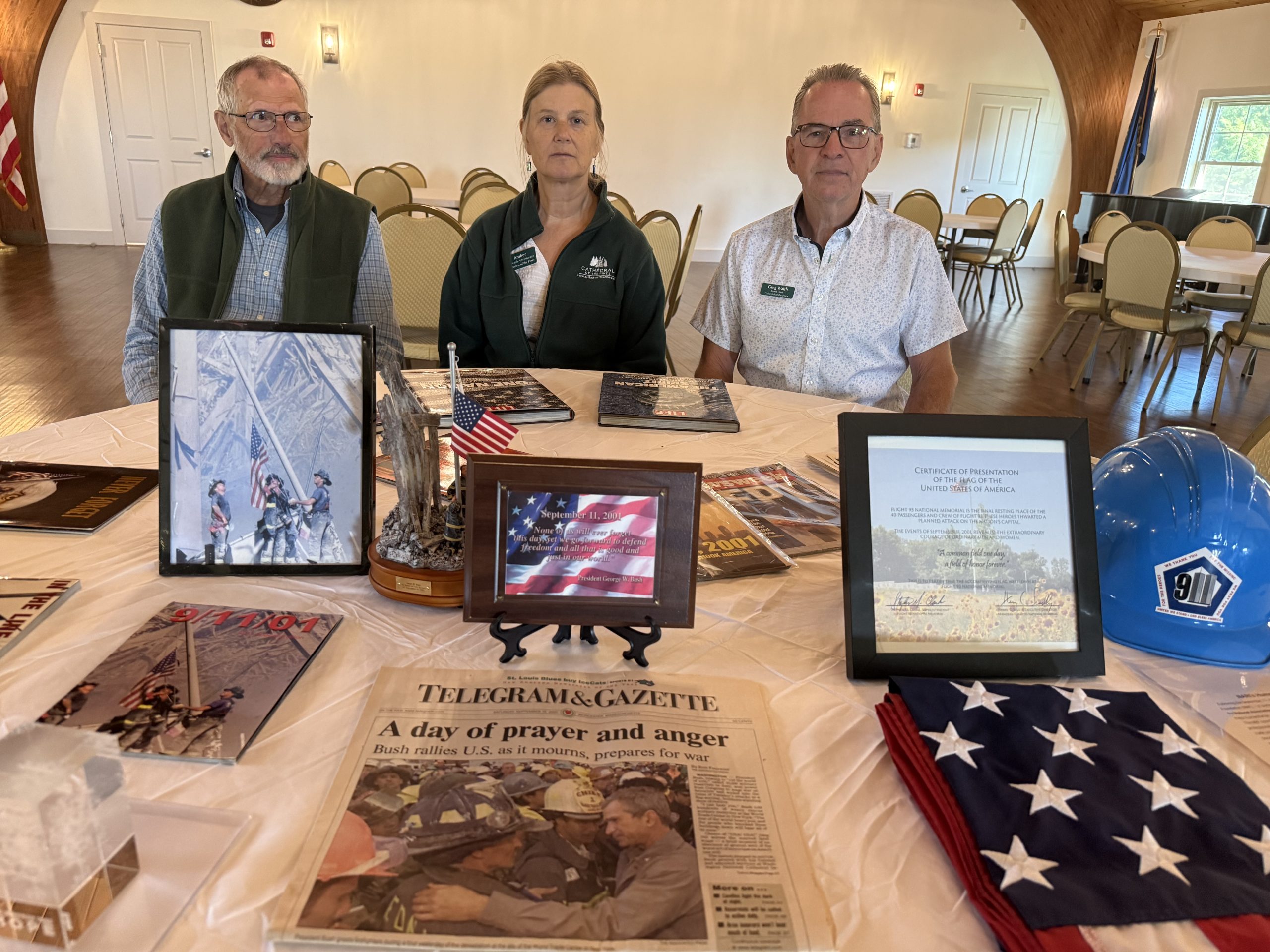 Cathedral of the Pines Interim Executive Director Trip Anderson, Outreach Administrator Amber Dewey and Board President Greg Walsh at a 9/11 memorial table at the Cathedral of the Pines.
