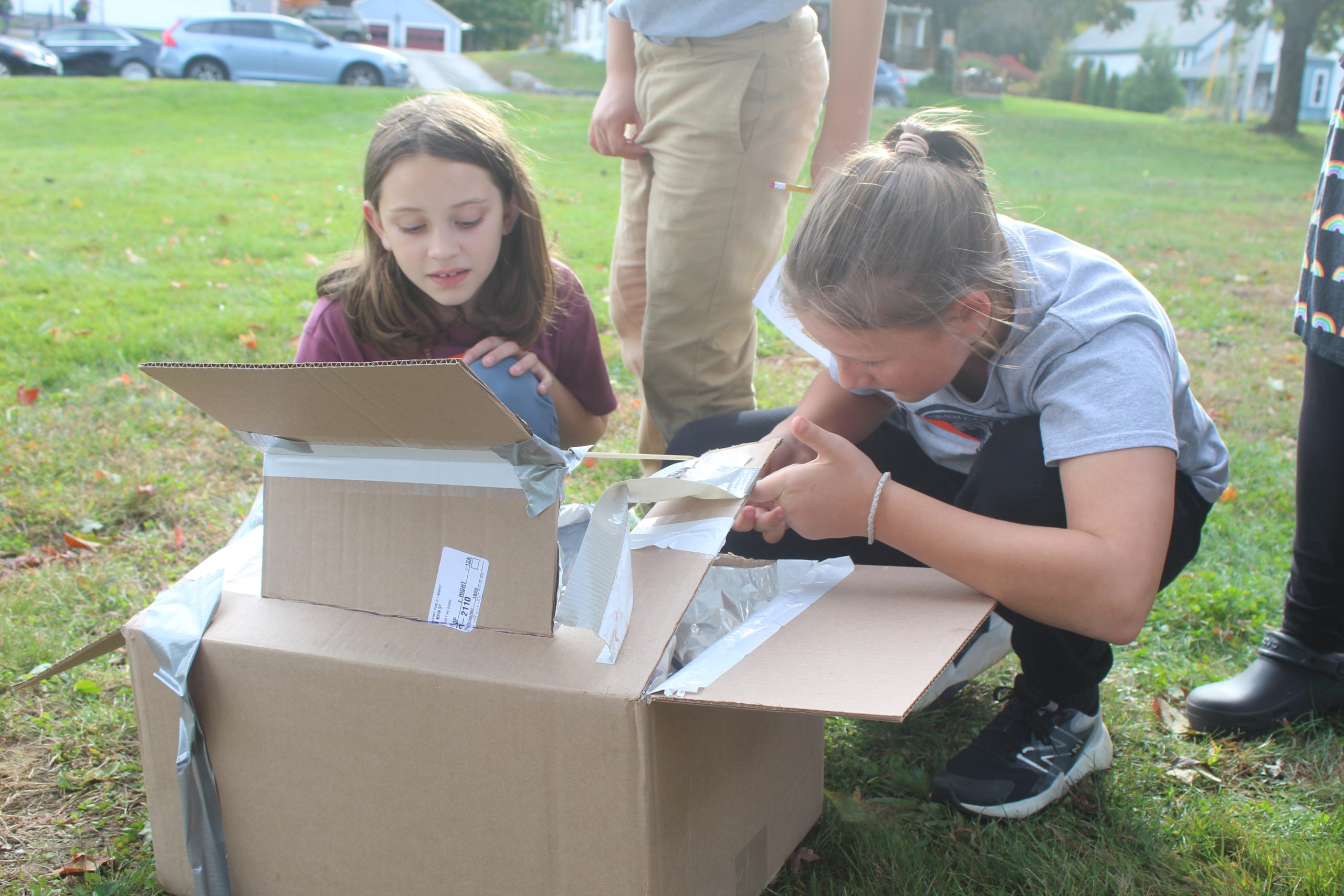 Gwen Kazanovicz and Annie Sprague open their solar oven.