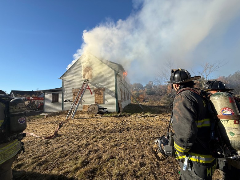 Crews watch as the house fills with smoke and fire.