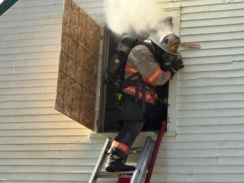 Ashby Fire Chief Brian Reichelt climbs out of the second story onto a ladder.