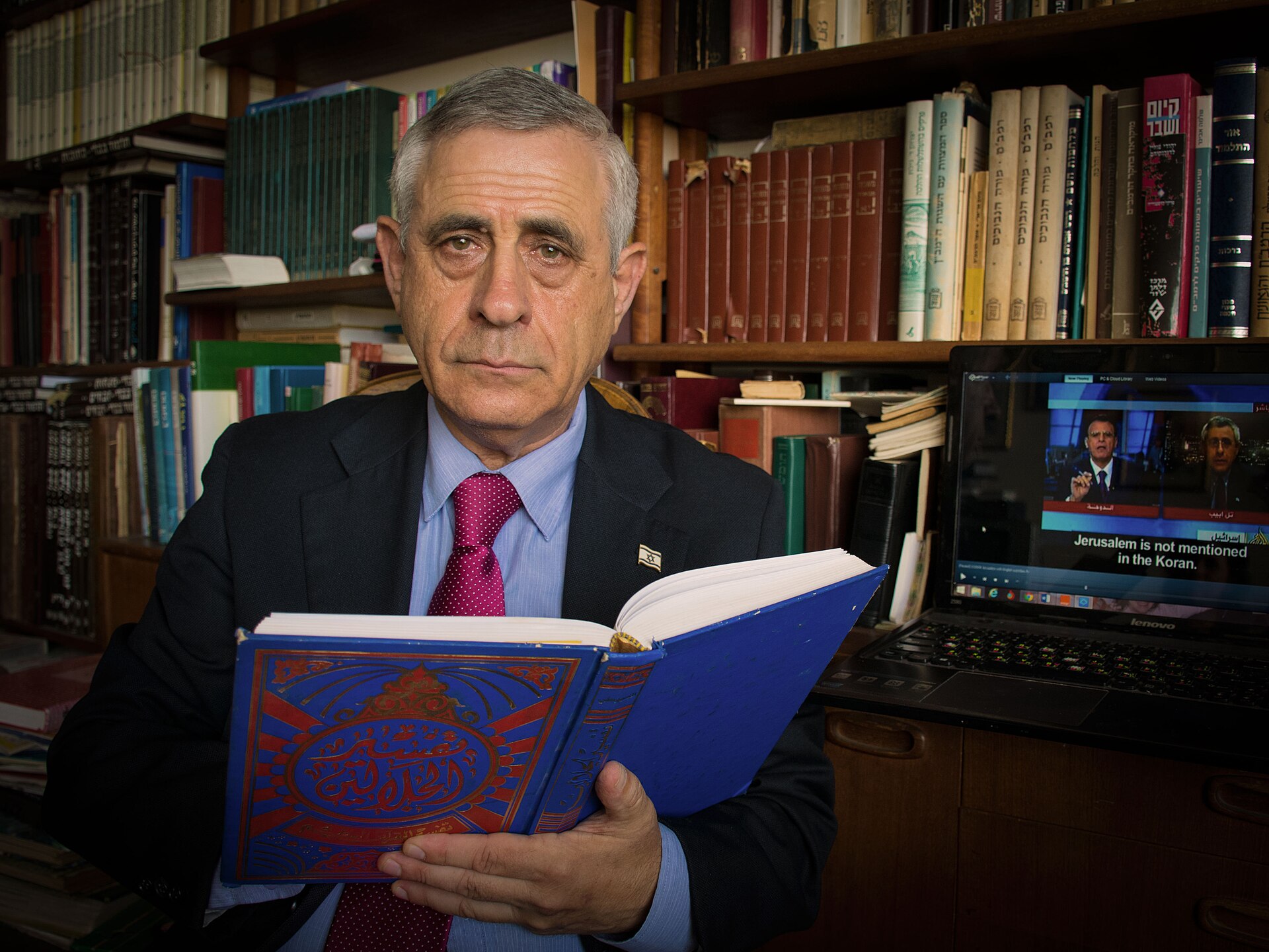 Mordechai Kedar dans sa bibliothèque, tenant un ouvrage en arabe
