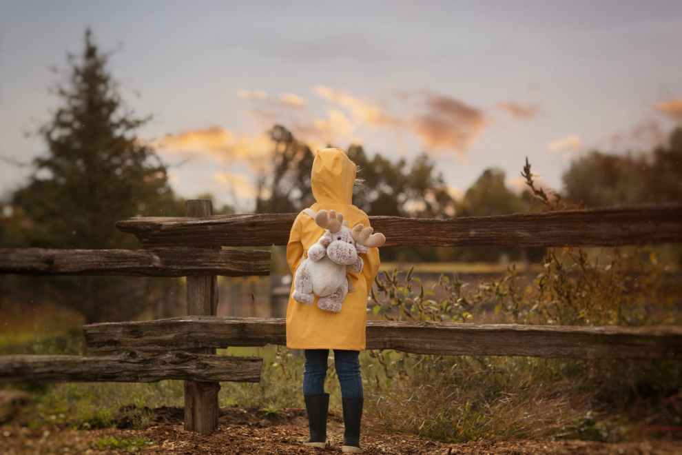 standing person carrying gray moose plush toy