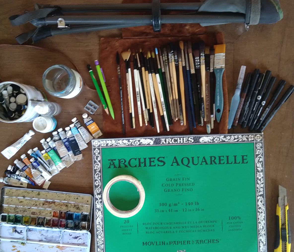 Matériel pour débuter l'aquarelle : papier Arches, pinceaux, palette, tubes d'aquarelle, trépied, cutter et accessoires.
