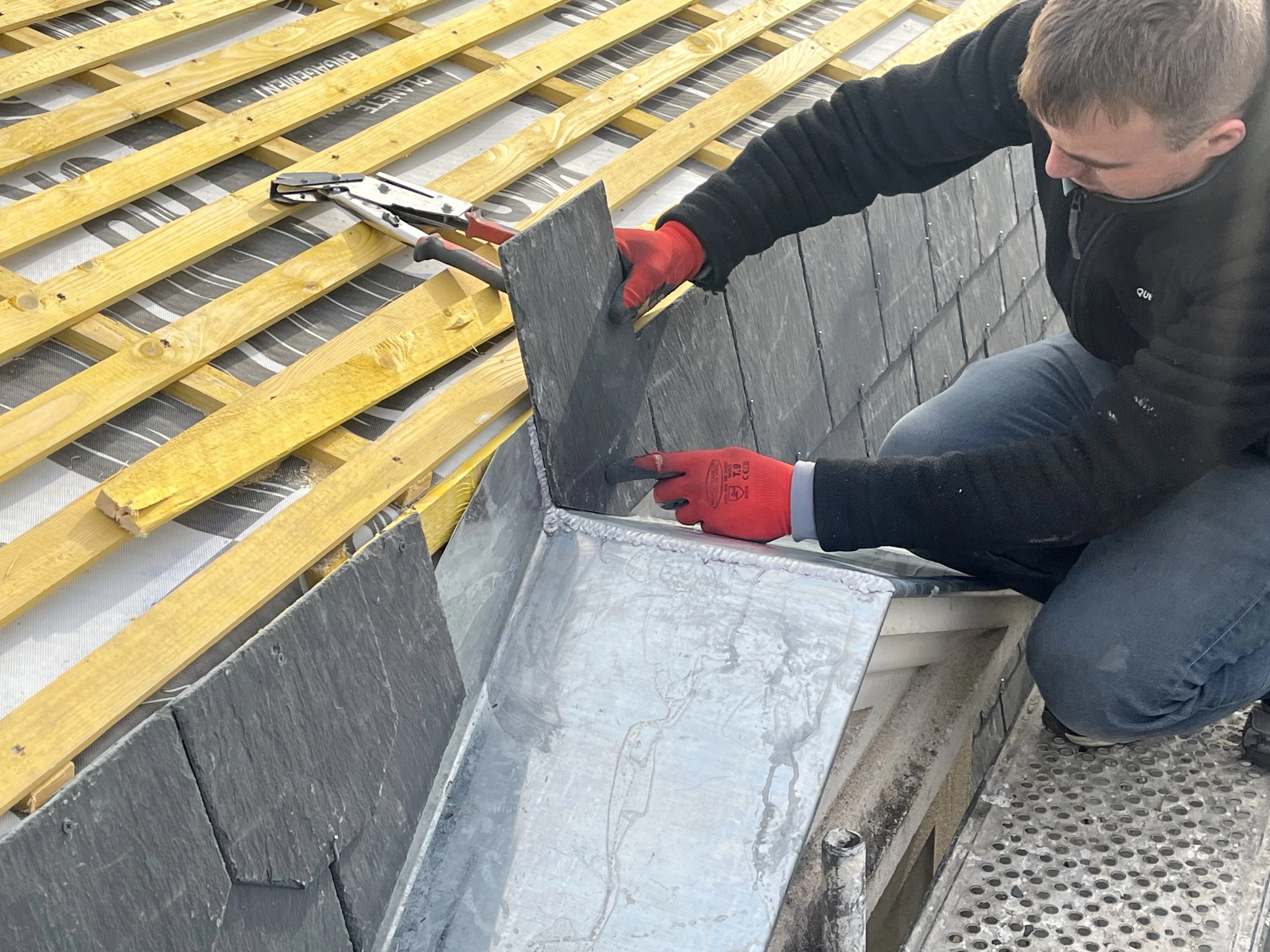Artisan couvreur réalisant avec précision une finition de toiture