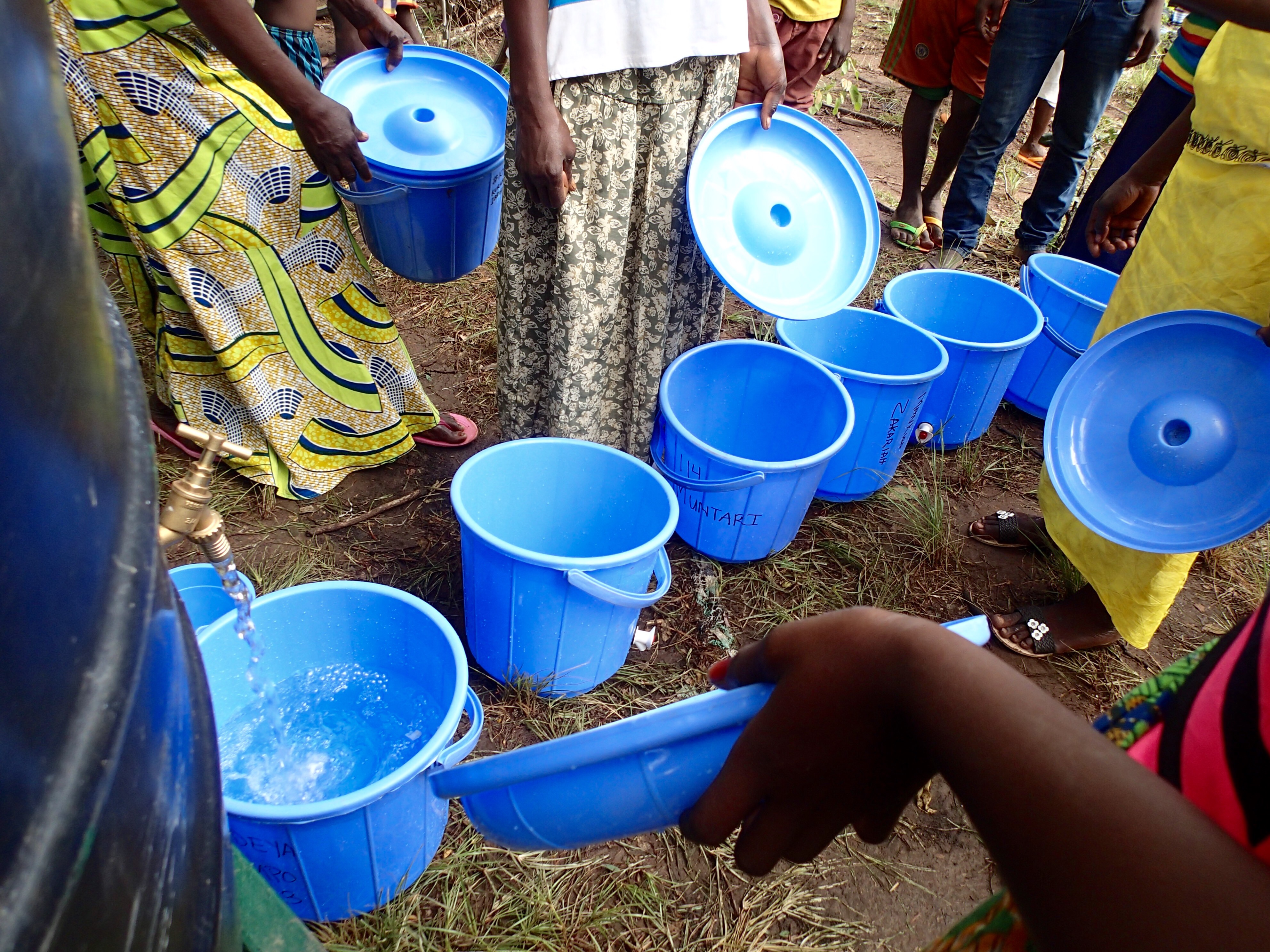 Village and Fulani women line up their safe storage containers for their first fill-up of clean water
