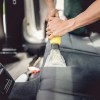 Technician shampooing vehicle upholstery seats