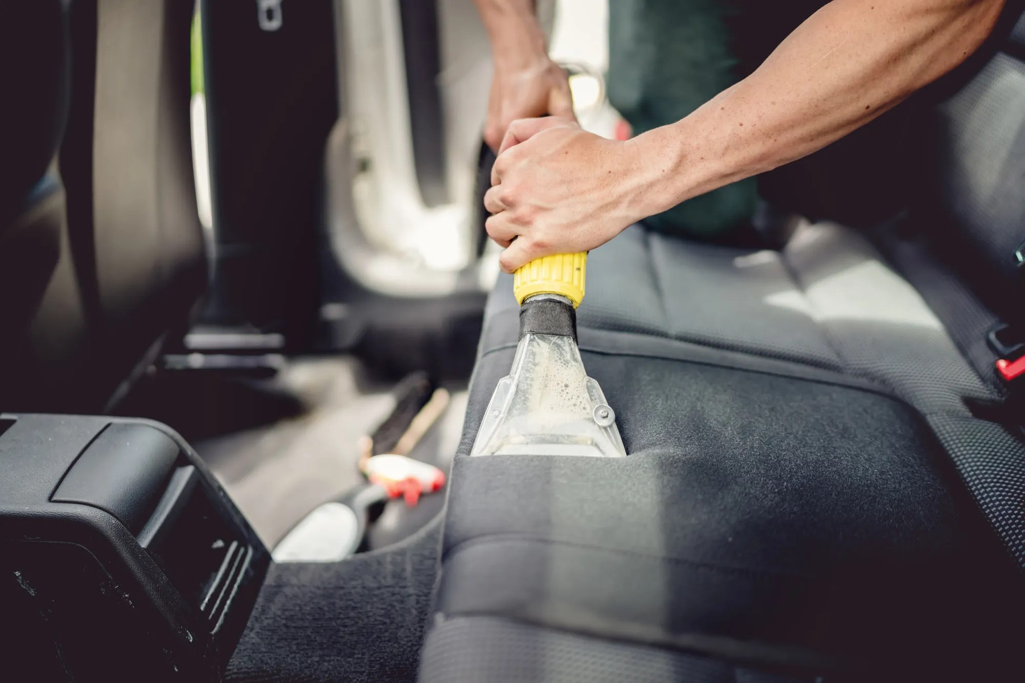 Technician shampooing vehicle upholstery seats