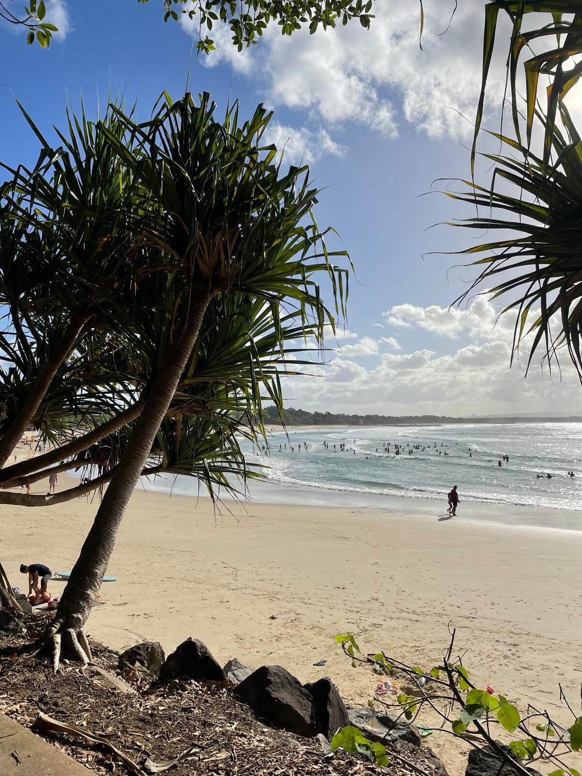 Travelers relaxing on Noosa Main Beach in Australia during the Ultimate East Coast Australia Itinerary, showing golden sand, clear water and coastal scenery.