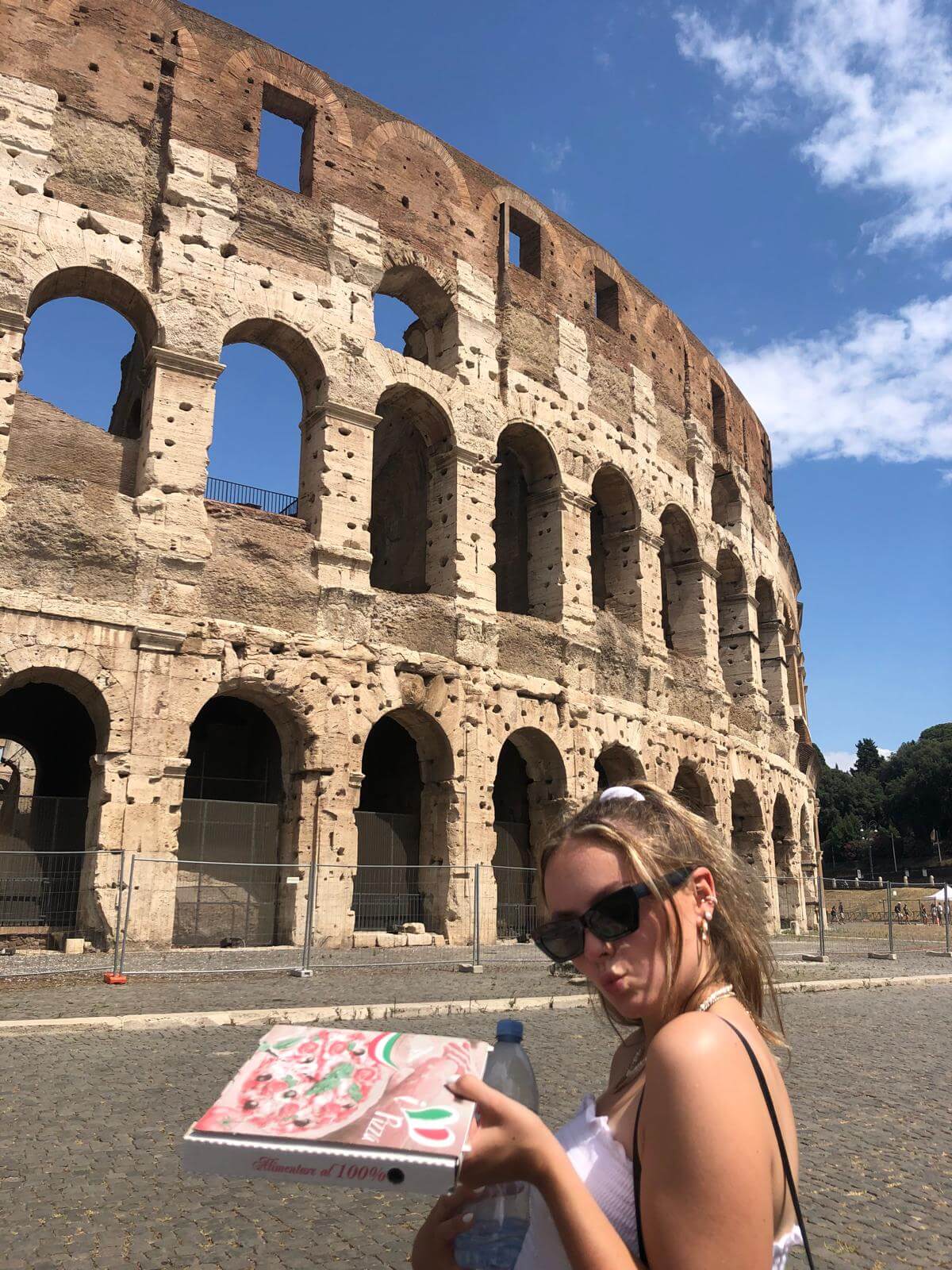 Holding a pizza box in front of the Colosseum in Rome