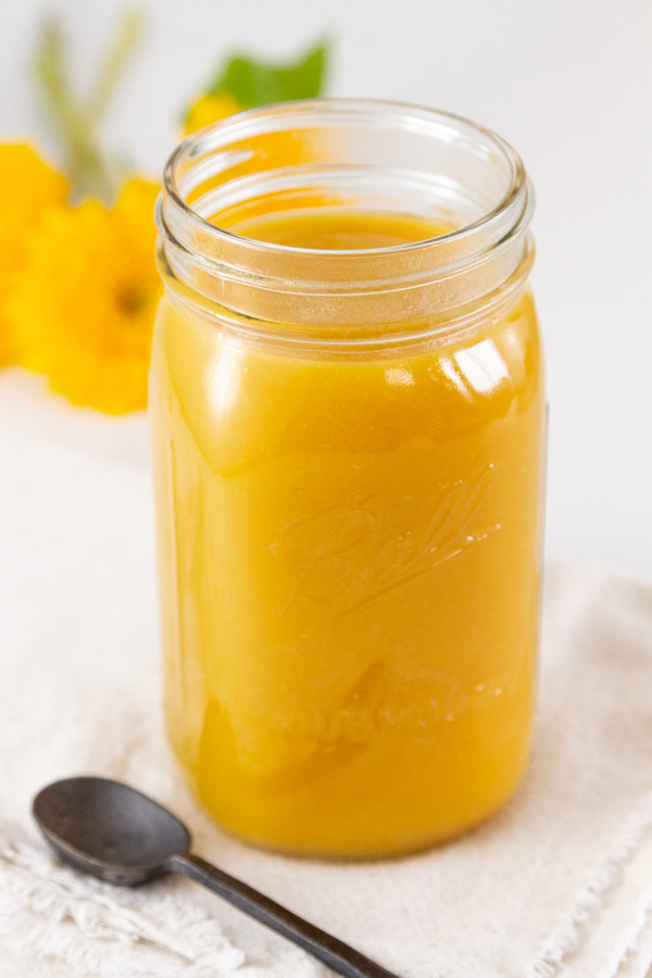 A large quart jar filled with fruit butter and a spoon next to it.