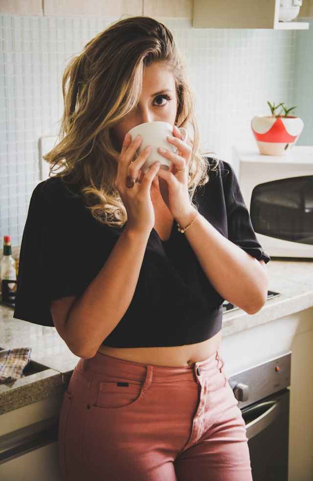 A young woman savoring her morning coffee in a cozy kitchen setting.