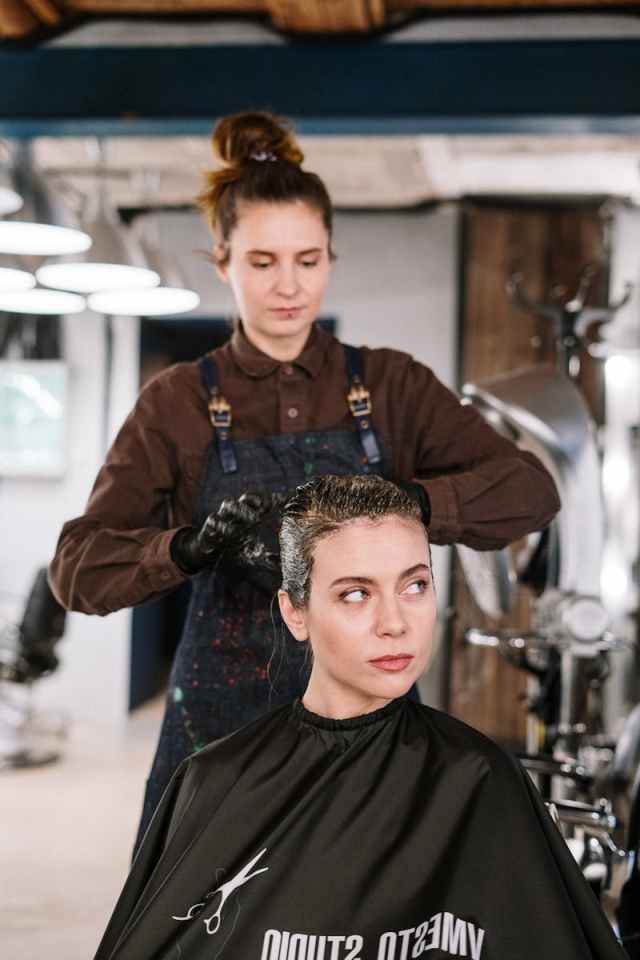 Hairdresser styling a woman's hair in a modern salon setting.