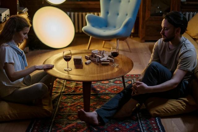 Couple enjoying a cozy game night at home with wine and a relaxing atmosphere.