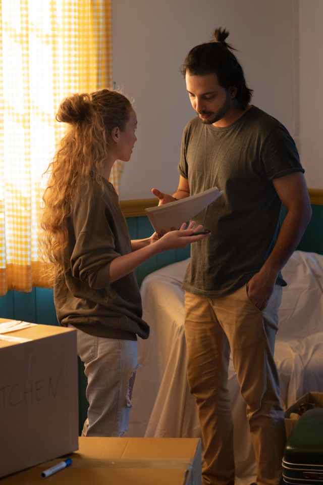 A couple discusses their moving plans in a cozy living room surrounded by boxes.