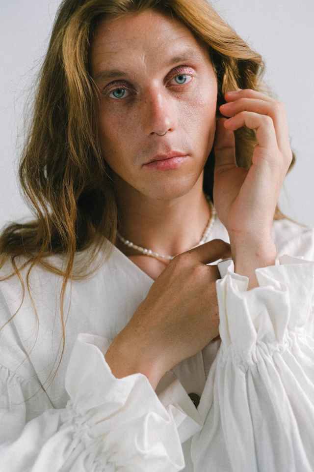 A serene portrait of an androgynous model with wavy hair in a studio setting.