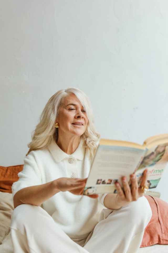 Elderly woman relaxing with a book, showcasing leisure and tranquility.