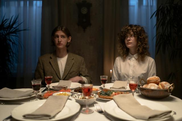 Two adults seated at a candlelit dinner table setting indoors, embodying tradition.