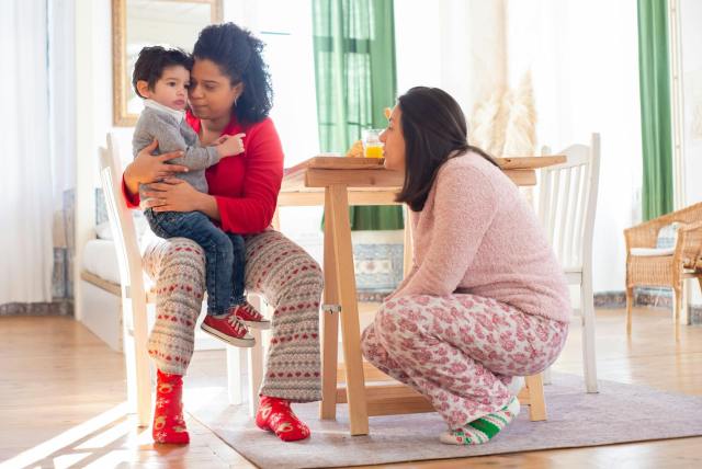 Mothers sit with their child in a cozy living room, creating a warm family moment.