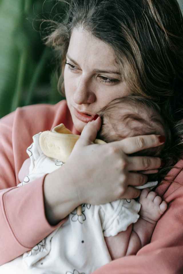 A loving mother holding her newborn baby at home, showcasing gentle maternal care.