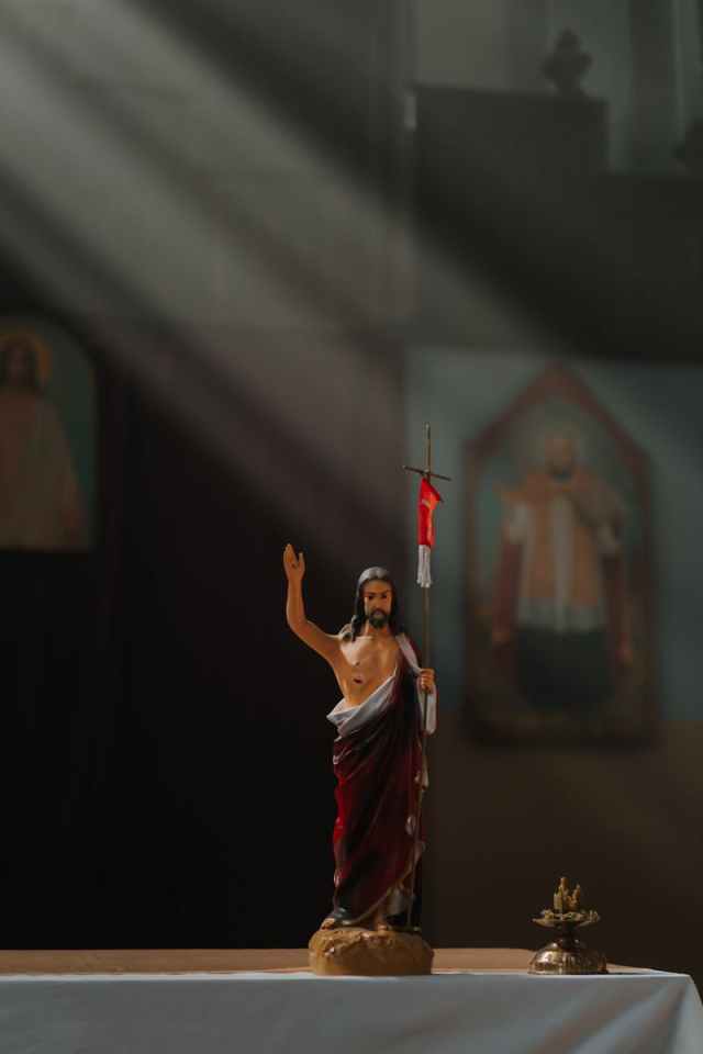 A statue of Jesus Christ inside a church with rays of sunlight illuminating the altar.
