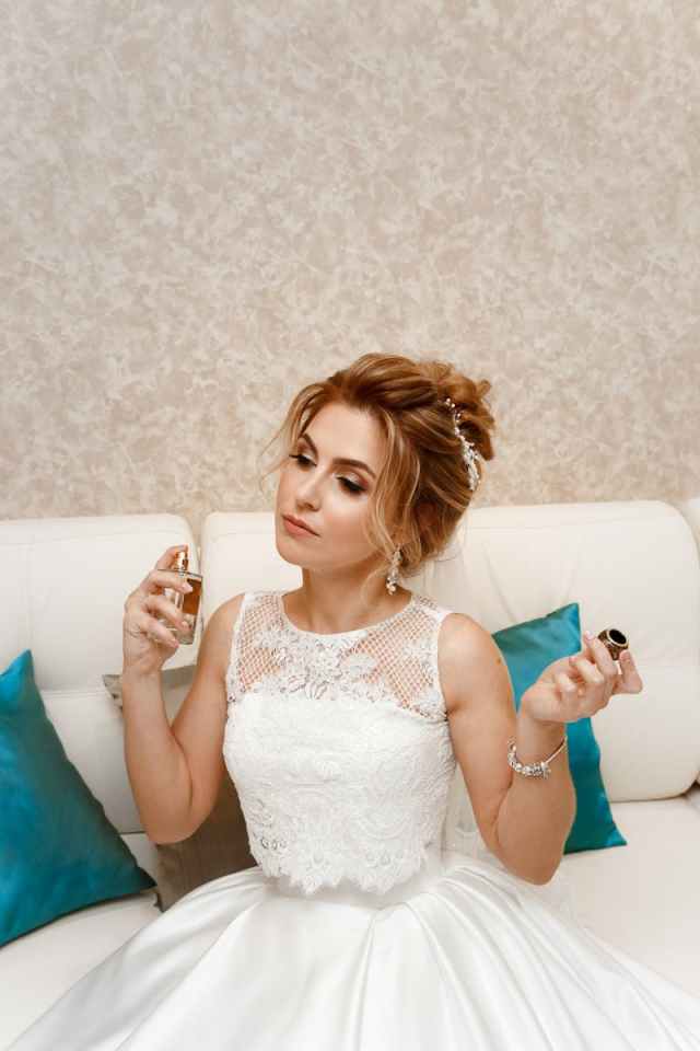 Beautiful woman in white dress applying perfume, exuding elegance.