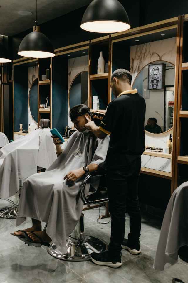 A barber cutting a client's hair in a contemporary barbershop setting.