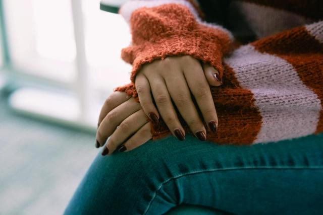 Close-up of a woman's hands resting on her lap wearing a warm sweater, conveying comfort and relaxation.