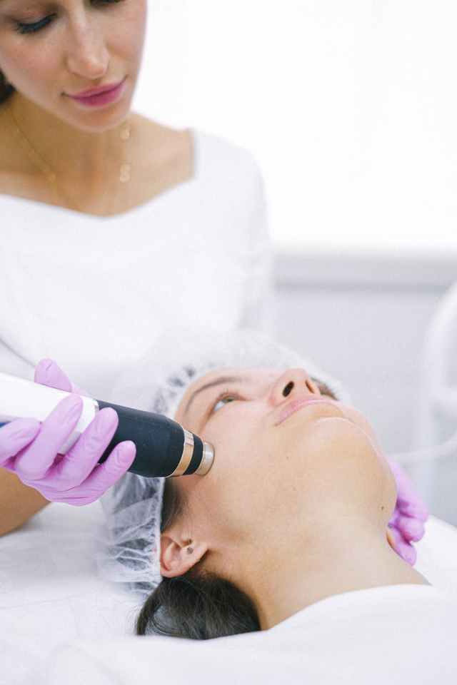 Woman receiving a high-tech laser skincare treatment in a clinical setting.