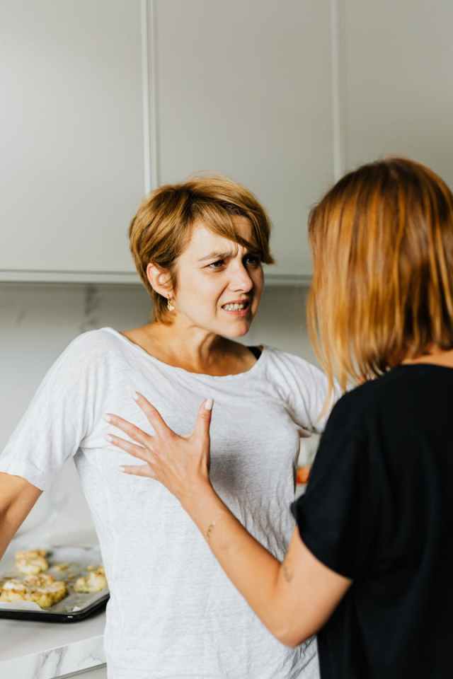 Two women engaged in a heated discussion in a modern kitchen.