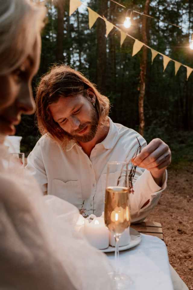 Couple enjoying a romantic dinner outdoors with candles and festive decorations.