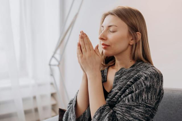 A serene woman practicing meditation indoors for relaxation and wellness.