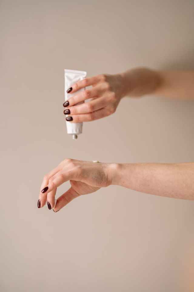 Close-up of a woman applying moisturizer to her hand for skincare routine.