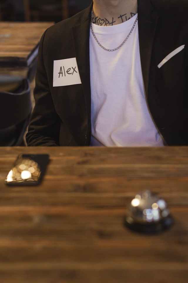 A person with a name tag sits at a wooden table, ready for a meeting.