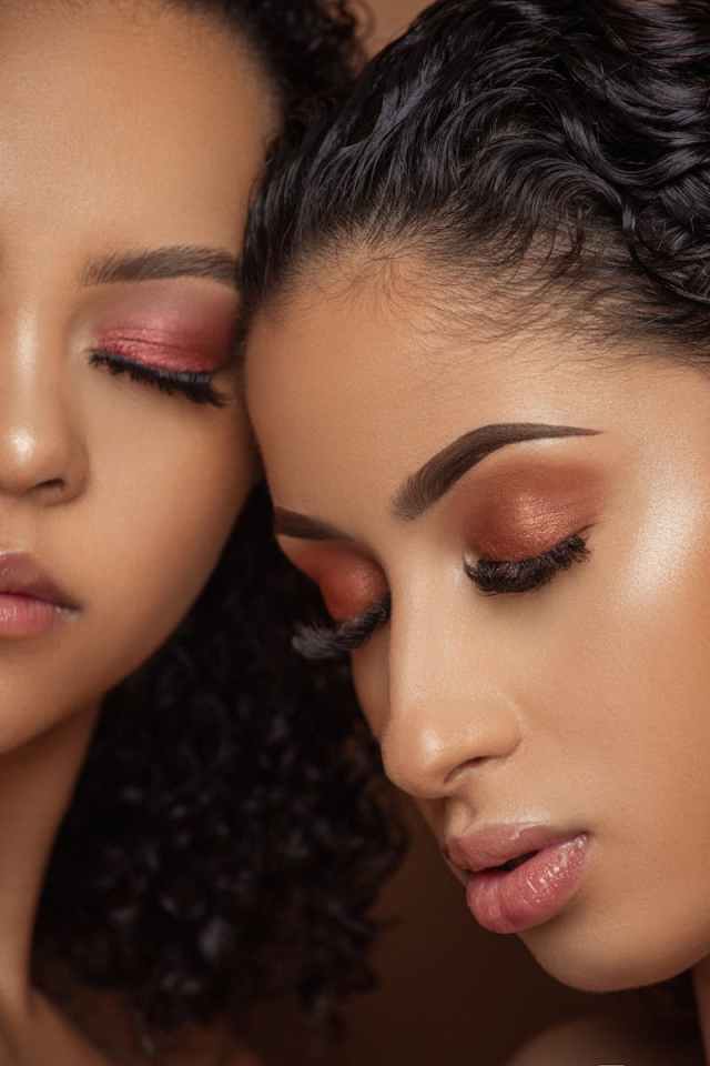 Close-up portrait featuring two women with artistic eye makeup, highlighting beauty and elegance.