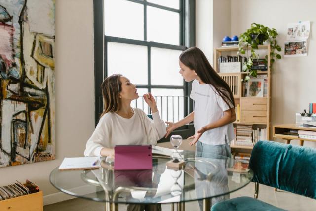A mother and teenage daughter engage in a discussion at home, capturing family dynamics and emotions.