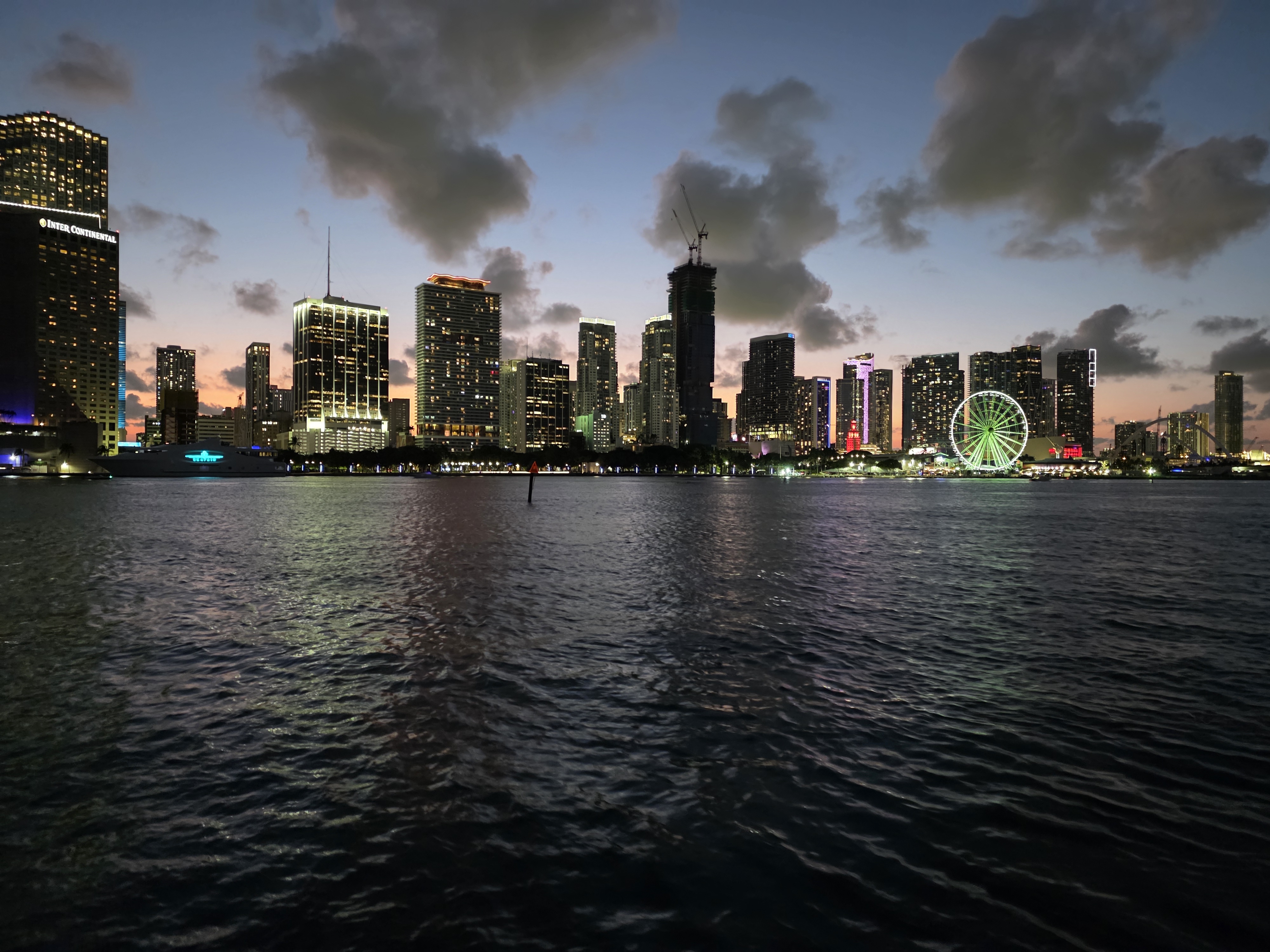 Miami skyline illuminated at night, photographed from a cruise on Biscayne Bay.