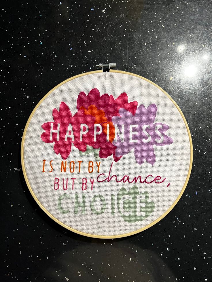 Completed cross-stitch of a Csaying "Happiness is not by chance, but by choice"