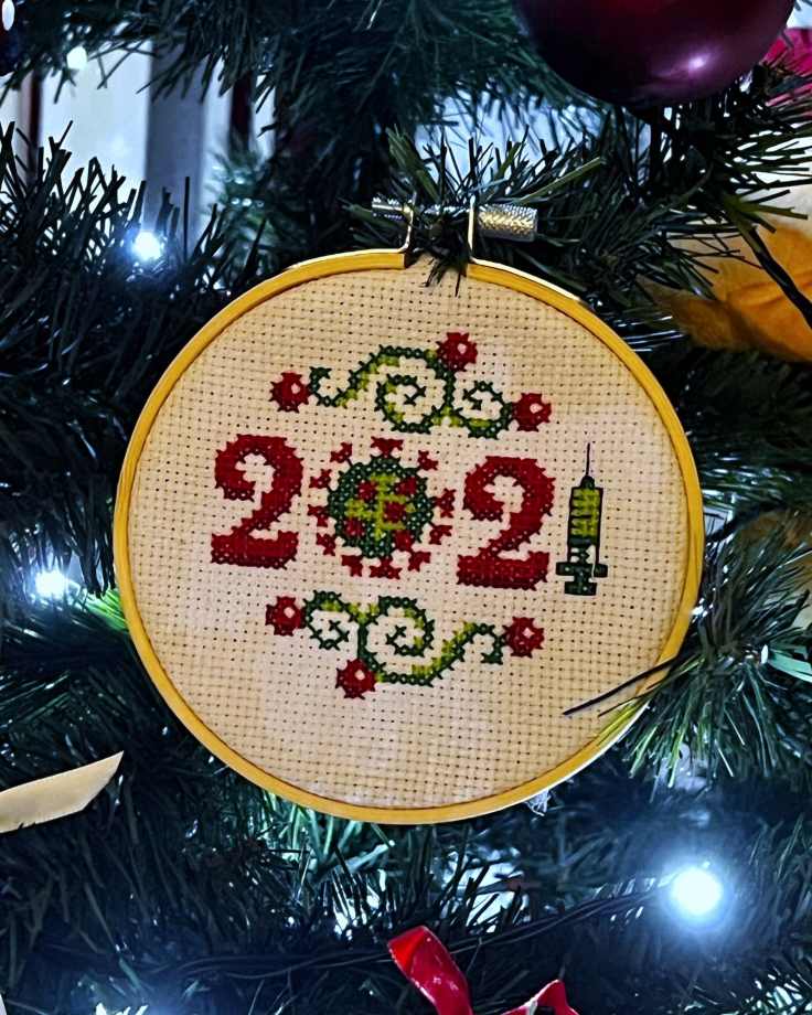 Completed cross-stitch of a 2021 - the zero has ben replaced with a bacteria while the 1 has been replaced by a syringe